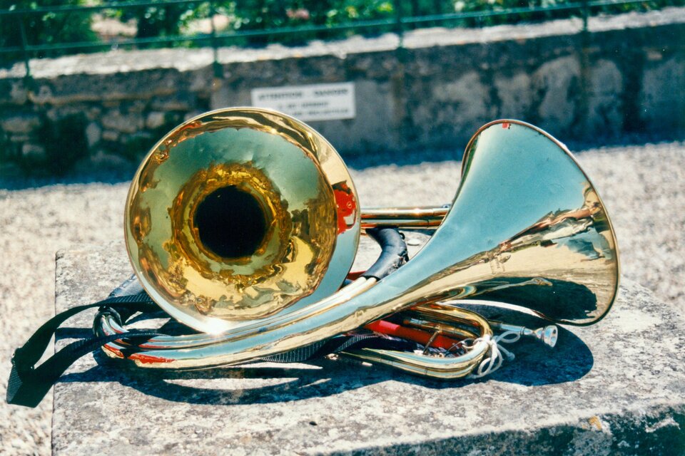 Ein glänzendes Blechblasinstrument liegt auf einer Steinmauer. Es reflektiert das Licht und zeigt die tiefen Farben der Umgebung. | © moap-hijpa-unsplash