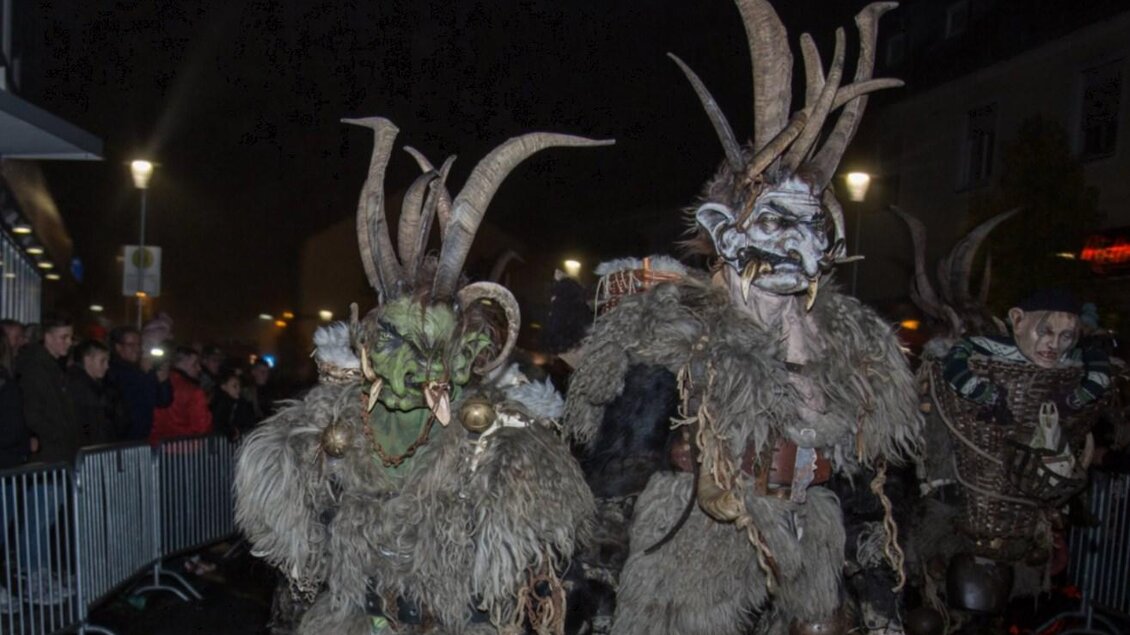 Eine Gruppe von Personen in eindruckvollen Kostümen mit Hörnern und furchterregenden Masken. Sie nehmen an einem festlichen Umzug in der Dunkelheit teil. | © Wabi - Gruam Teifln