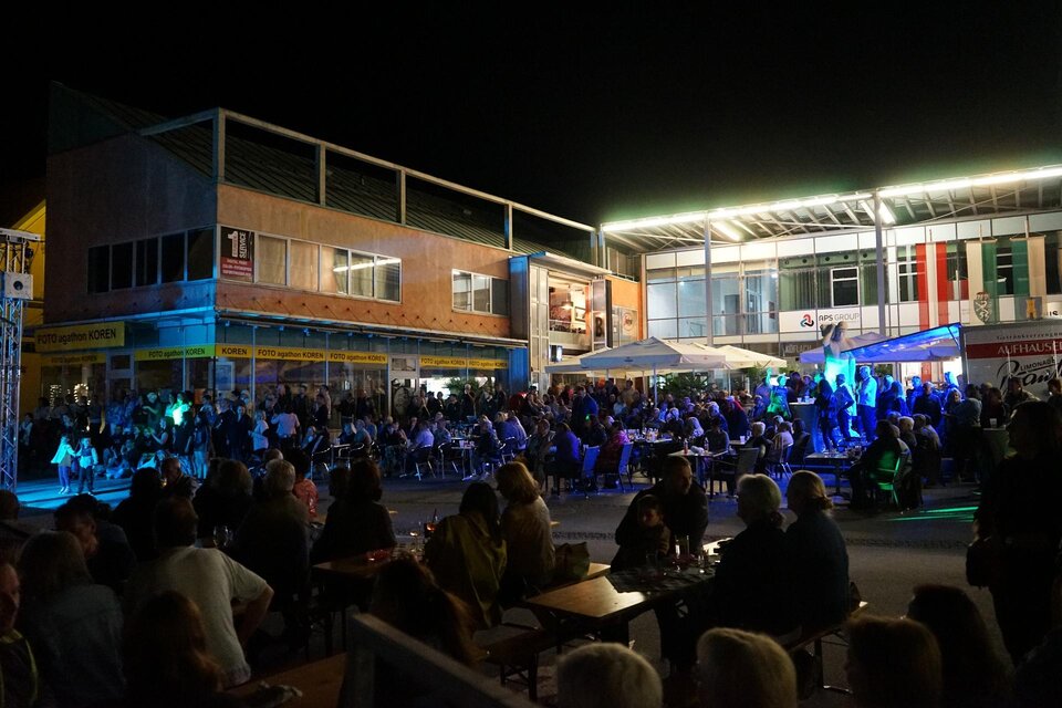 Eine lebhafte Nachtveranstaltung mit einer großen Menschenmenge. Die Atmosphäre ist festlich, beleuchtet von bunten Lichtern. | © Stadtgemeinde Köflach