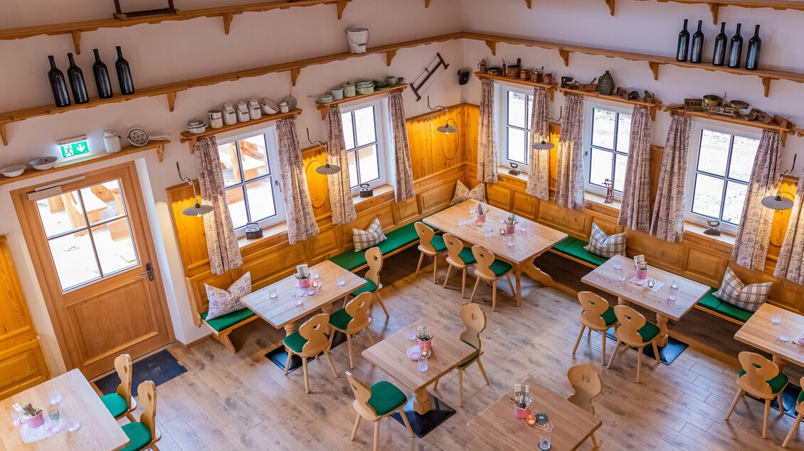 Ein gemütliches Restaurant mit Holzmöbeln und Fenster mit Vorhängen. Die Tische sind schön gedeckt und die Wände sind mit dekorativen Elementen geschmückt. | © www.zloamwirt.at