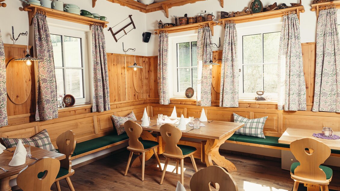 Ein gemütliches Restaurant mit Holzinterieur und traditionellen Tischen. Die Fenster sind mit Vorhängen geschmückt und die Einrichtung strahlt eine einladende Atmosphäre aus. | © www.zloamwirt.at