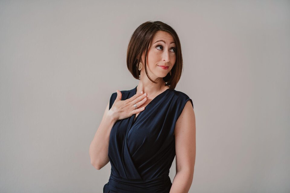 Eine Frau in einem eleganten, dunkelblauen Kleid schaut neugierig zur Seite. Sie hat einen selbstbewussten Ausdruck und eine handgestützte Geste. | © lynephptpgraphy