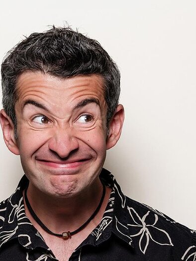 A man with a quirky facial expression stands in front of a neutral background. He is wearing a short-sleeved shirt with a floral pattern. | © Stefan Gergely