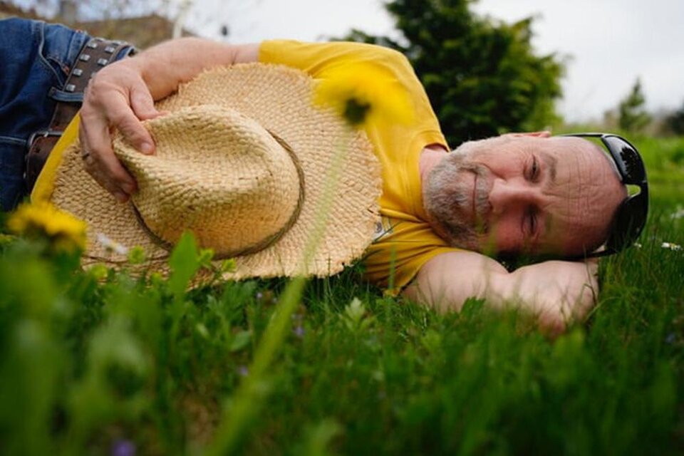 Ein Mann liegt entspannt auf dem Gras und trägt einen Strohhut. Er genießt die Natur an einem sonnigen Tag. | © Tom-Tom Lachmayr