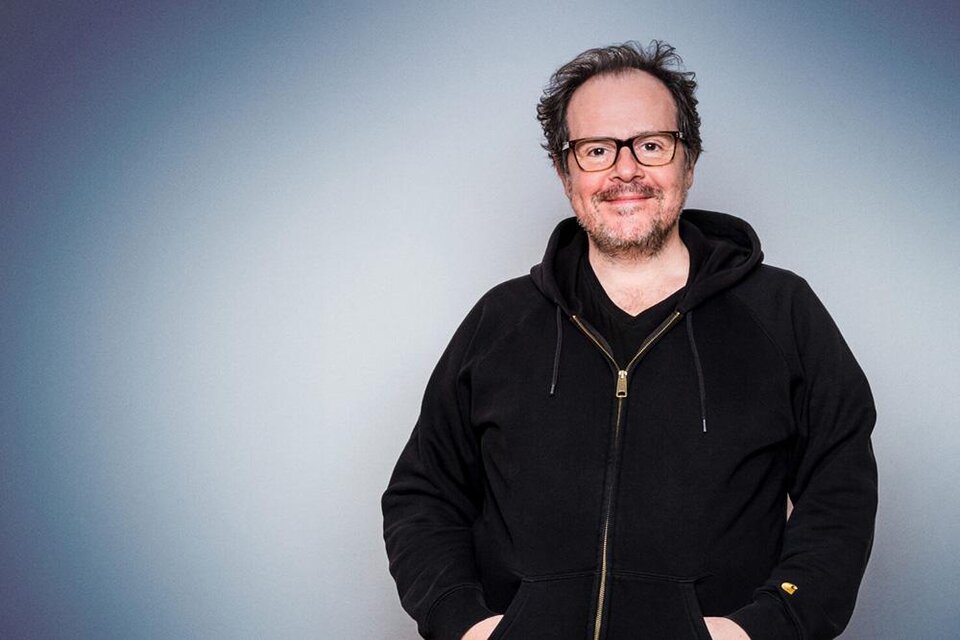 Ein lächelnder Mann mit Brille trägt einen schwarzen Hoodie. Der Hintergrund ist in sanften Grautönen gehalten. | © Thomas Mraz