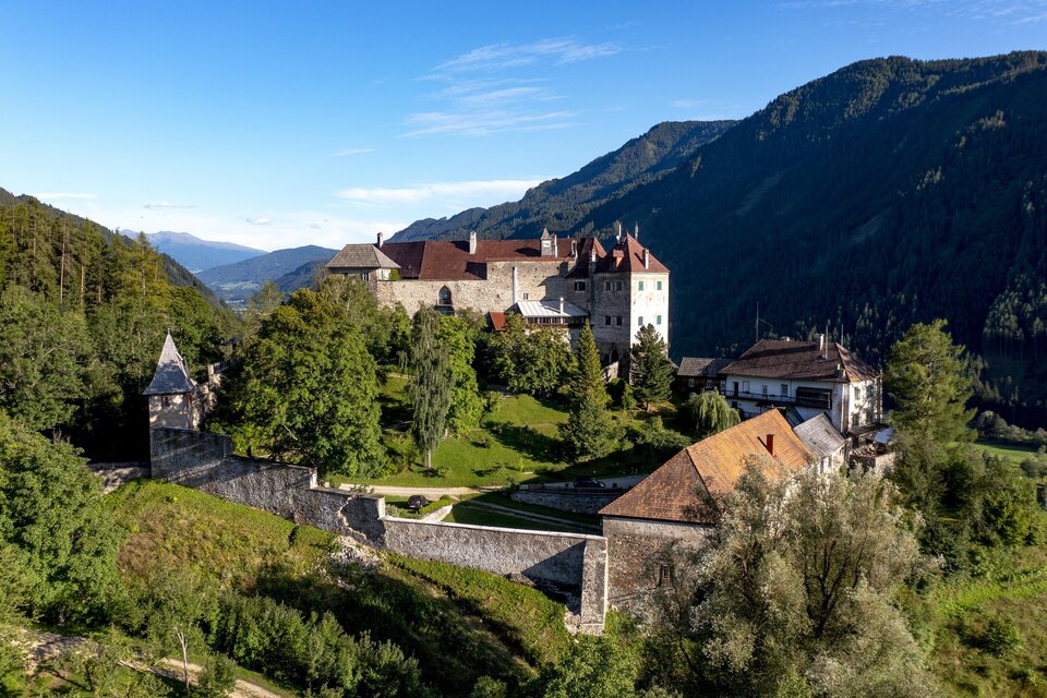 Eine beeindruckende Burg umgeben von Wäldern und Bergen. Der klare Himmel lässt die Landschaft strahlend erscheinen. | © TV Murau