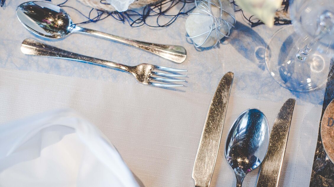 Ein festlich gedeckter Tisch mit glänzendem Besteck und gläsernen Accessoires. Die Tischdecke ist hell und elegant. | © Garten Hotel Ochensberger