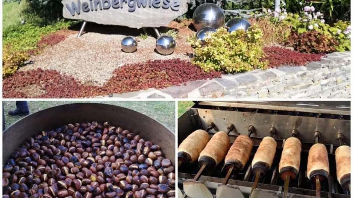 Eine Begrüßungstafel "Weinbergwiese" umgeben von Blumen und dekorativen Kugeln. Darunter sind geröstete Kastanien und Backwaren auf einem Grill zu sehen. | © Walter Patzelt