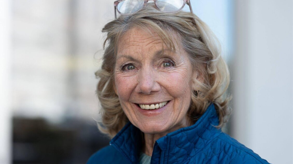 Ein Foto von Erika Deutinger, welche an diesem Abend die Rezitation des Lebensbildes von Katia Mann gestaltet. Sie lächelt und trägt eine blaue Jacke, hat eine positive Ausstrahlung und schaut freundlich in die Kamera. | © Erika Deutinger