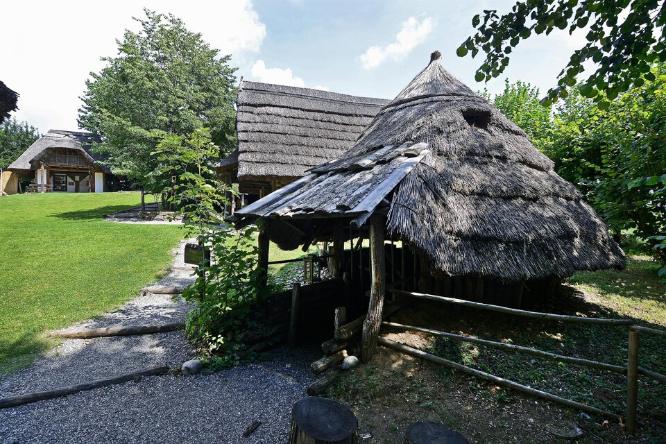 Ein traditionelles, strohgedecktes Haus steht in einer grünen Umgebung. Im Hintergrund sind weitere Gebäude und viel Natur zu sehen. | © Kulmkeltendorf