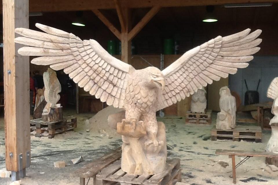 Eine kunstvolle Skulptur eines Adlers mit ausgebreiteten Flügeln steht in einer Werkstatt. Der Adler zeigt detailreiche carvierte Merkmale und ist auf einer Holzpalette platziert. | © Günther Friedrich