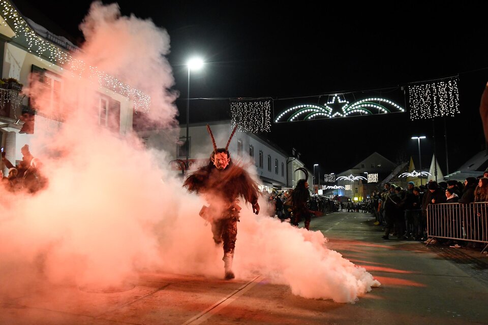 Eine Person läuft durch eine rauchige Straße bei Nacht. Im Hintergrund sind Lichter und Verkaufsstände zu sehen. | © Stadtgemeinde Kindberg