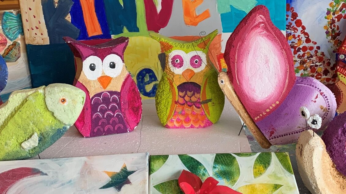 Bunte Kunstwerke und Handarbeiten sind auf einem Tisch ausgestellt. Es gibt verschiedene Figuren wie Eulen, Fische und Schnecken, die alle kreativ gestaltet sind. | © Marlene Schaumberger