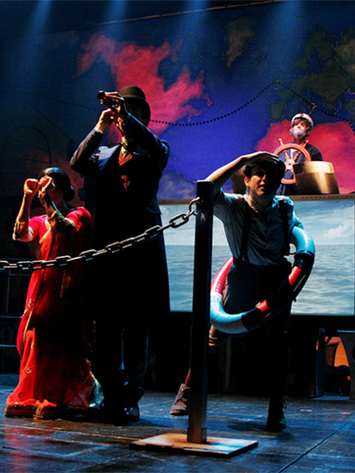 A theater performance with three actors in historical costumes. They stand in front of a submarine and look into the distance through telescopes. | © Theater mit Horizont