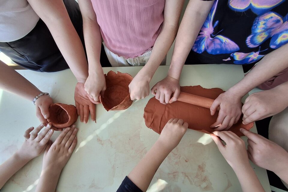 Eine Gruppe von Menschen arbeitet mit Ton auf einem Tisch. Ihre Hände formen verschiedene Objekte aus dem Material. | © Vesna Vesel
