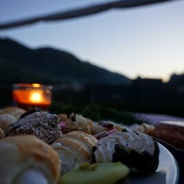 Zu sehen ist ein Teller mit Kuchen und ein Teelicht in der Dämmerung. | © Gemeinde Ratten