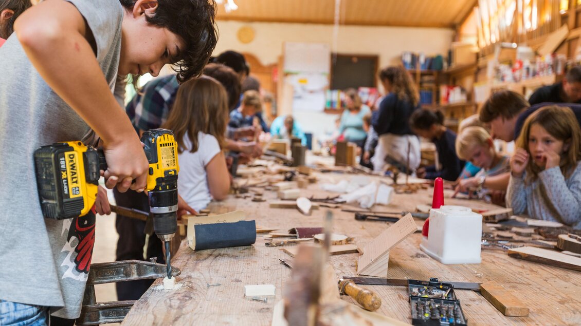 Kinder arbeiten in einer Holzwerkstatt. Sie verwenden Werkzeuge, um kreative Projekte zu erstellen. | © Dominik Steiner
