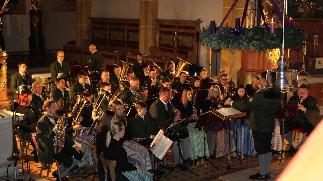 Ein Blasorchester spielt in einer Kirche. Die Musiker sind in festlicher Kleidung und konzentrieren sich auf den Dirigenten. | © MV Graßnitz