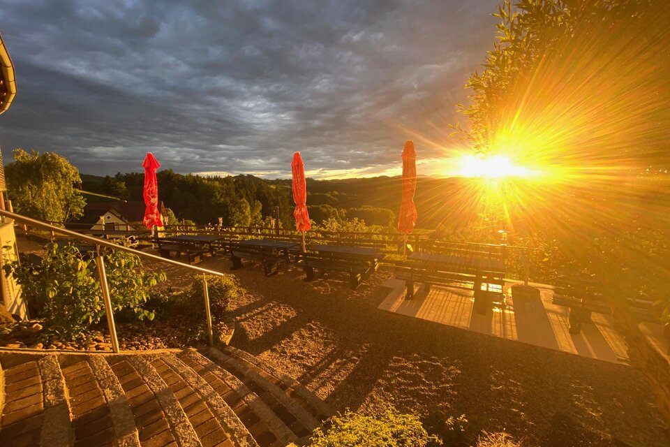 Ein malerischer Aussichtspunkt mit Stufen und grünen Pflanzen. Im Hintergrund scheint die Sonne und erzeugt eine warme, goldene Atmosphäre. | © Eckbergerhof
