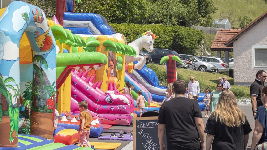 Eine lebendige Spielstraße mit mehreren bunten Hüpfburgen und Rutschen. Kinder spielen fröhlich, während Erwachsene zuschauen. | © (c) Thomas Brand