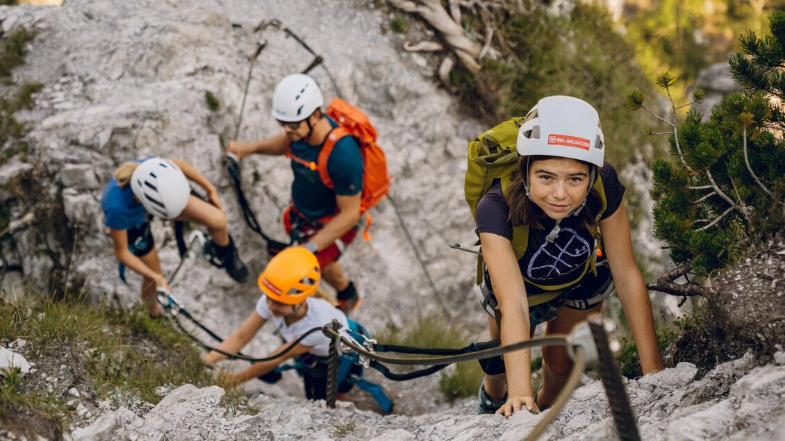 Eine Gruppe von Kletterern erklimmt einen steilen Felsen. Die Personen tragen Helme und Kletterausrüstung und sind in einer natürlichen Umgebung. | © Christine Höflehner