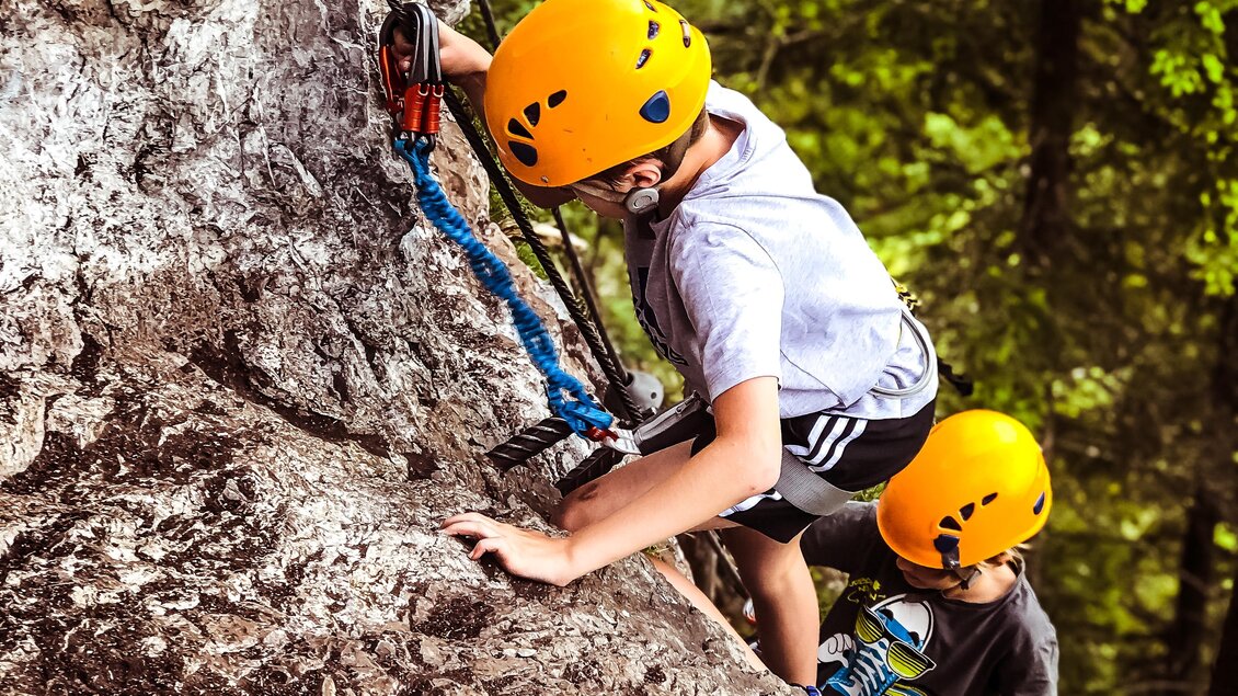 Zwei Kinder klettern an einer Felswand. Sie tragen Helme und sind mit Sicherheitsseilen gesichert. | © Tourismusverband Schladming-Dachstein