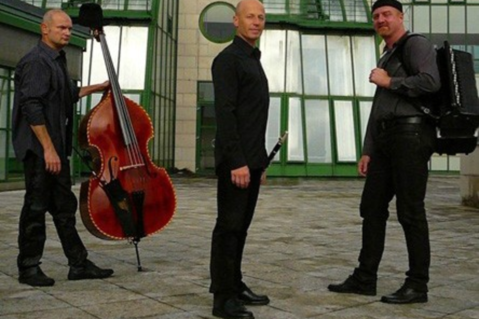 Fünf Musiker in Schwarz-Weiß, die verschiedene Instrumente spielen. Die Bilder zeigen einen Schlagzeuger, einen Gitarristen, einen Pianisten, eine Sängerin und einen weiteren Musiker. | © Kelzmer Connection Trio