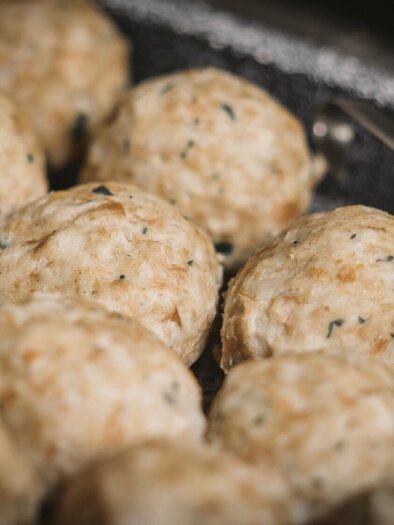 A collection of round dough balls can be seen. They are light brown and appear to be freshly made.