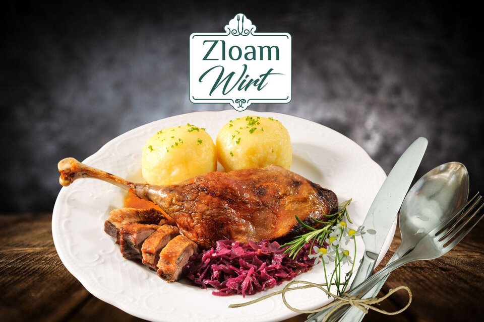 Ein köstlicher Teller mit gebratener Ente, Rotkohl und Kartoffelknödeln. Im Hintergrund ist das Logo "Zloam Wirt" sichtbar. | © www.zloam.at