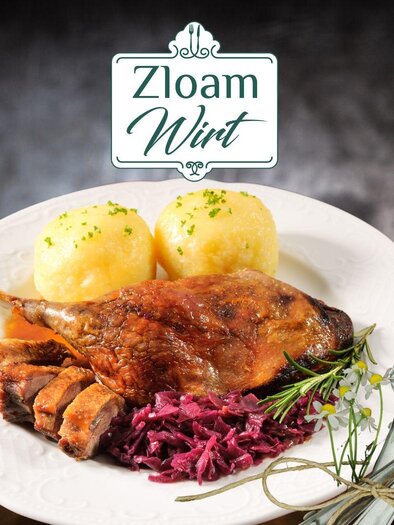Ein köstlicher Teller mit gebratener Ente, Rotkohl und Kartoffelknödeln. Im Hintergrund ist das Logo "Zloam Wirt" sichtbar. | © www.zloam.at