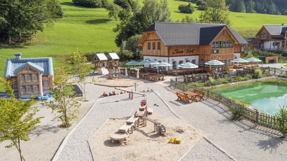 Ein gemütliches Restaurant in ländlicher Umgebung mit einem Spielplatz und einem kleinen Teich. Die grüne Landschaft um das Gebäude lädt zum Entspannen ein. | © www.zloam.at
