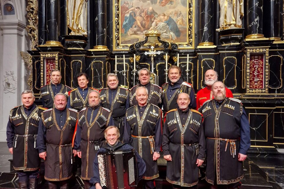 Eine Gruppe von Männern in traditioneller Kleidung steht vor einem prächtigen Altar. Der Boden ist mit rotem Teppich bedeckt und im Hintergrund ist ein kunstvolles Gemälde zu sehen. | © Bolschoi Don Kosaken
