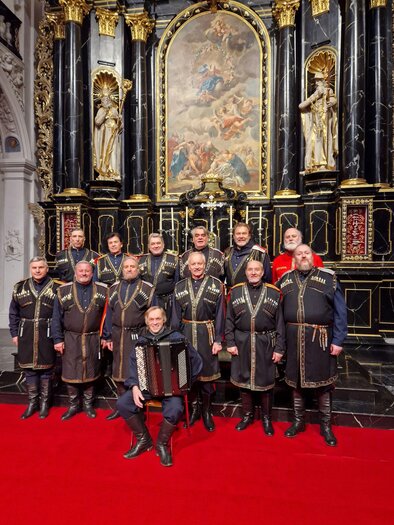 A group of men in traditional clothing stands in front of a magnificent altar. The floor is covered with a red carpet and in the background, there is an ornate painting. | © Bolschoi Don Kosaken