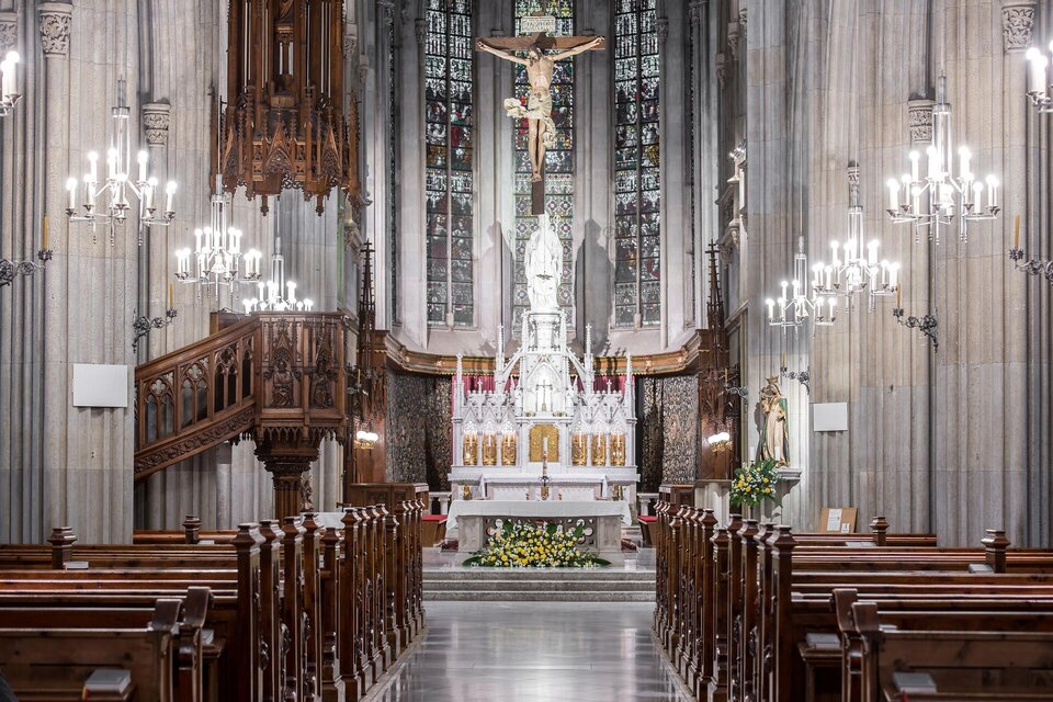 Ein eleganter Kirchenraum mit Holzbankreihen und einem auffälligen Altar. Die Wände sind aus Stein, und die Beleuchtung sorgt für eine ruhige Atmosphäre. | © TV Gesäuse