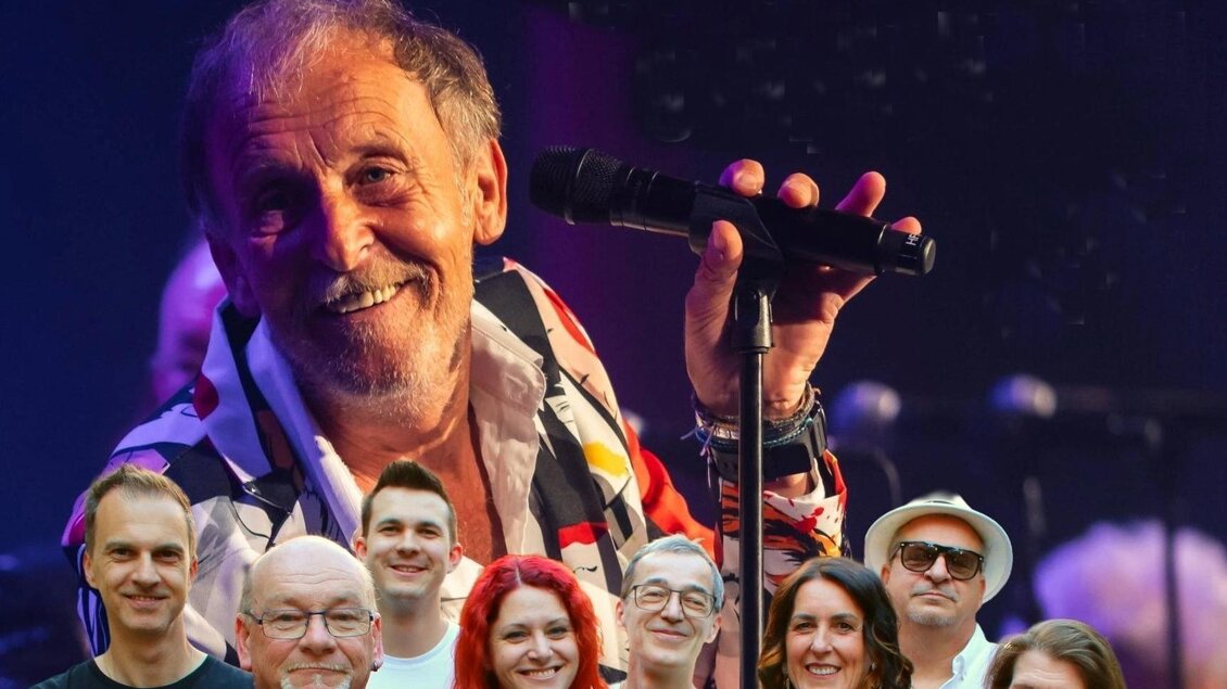 Eine Gruppe von Menschen steht zusammen, während ein Sänger im Hintergrund auftritt. Alle wirken fröhlich und begeistert von der Musik. | © Burgruine Waxenegg