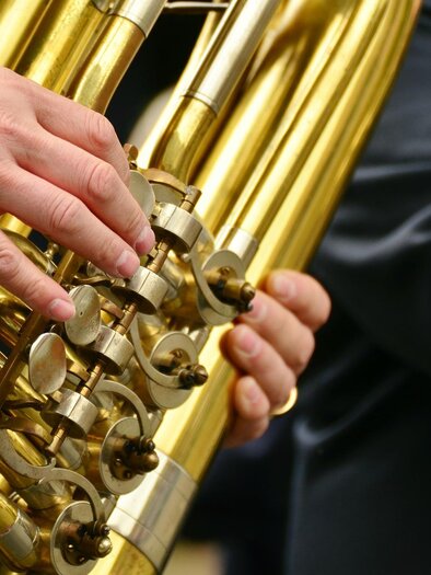 A musician is playing a shiny tuba. The musician's hands are gripping the valves of the instrument. | © Pixabay