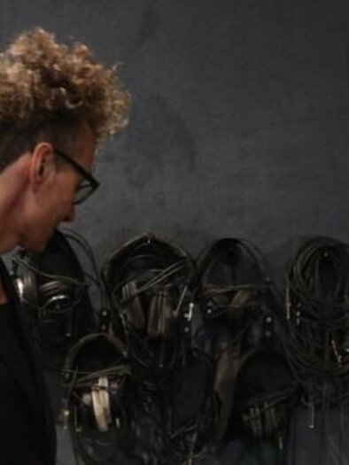 Eine Person spielt Cello in einer belebten Umgebung. Man sieht nur die Hände und das Instrument, während Menschen im Hintergrund vorbeigehen. | © Andrea Schumi