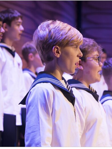 Eine Gruppe von Jungen in Matrosenanzügen singt in einem Chor. Die Szenerie ist festlich und die Jungen zeigen konzentrierte Gesichtsausdrücke. | © Lukas Beck