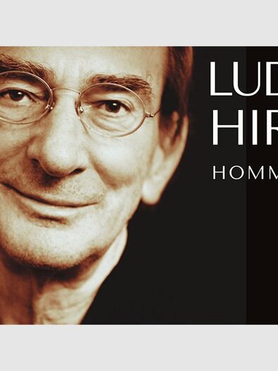 A portrait of Ludwig Hirsch, smiling at the camera. The background is in dark tones and there is an inscription honoring his 80th birthday. | © Universal Music
