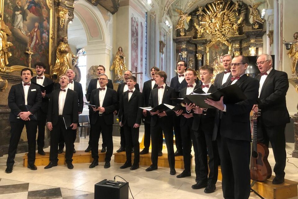 Die Gentlemen Voices präsentieren sich bei einem stimmungsvollen Auftritt in festlicher Atmosphäre im Kulturhaus Bad Waltersdorf. In eleganten Anzügen sorgt das Männerensemble vor der prachtvollen Kulisse einer Kirche für ein besonderes musikalisches Erlebnis. | © Gentlemen Voices