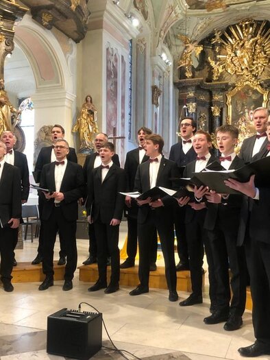 The Gentlemen Voices present themselves in a lively performance in a festive atmosphere at the Kulturhaus Bad Waltersdorf. In elegant suits, the male ensemble provides a special musical experience against the magnificent backdrop of a church. | © Gentlemen Voices