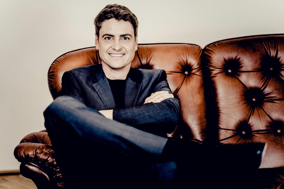 Porträt des Pianisten Christoph Traxler, der auf einem braunen Ledersofa sitzt. | © Andrej Grilc