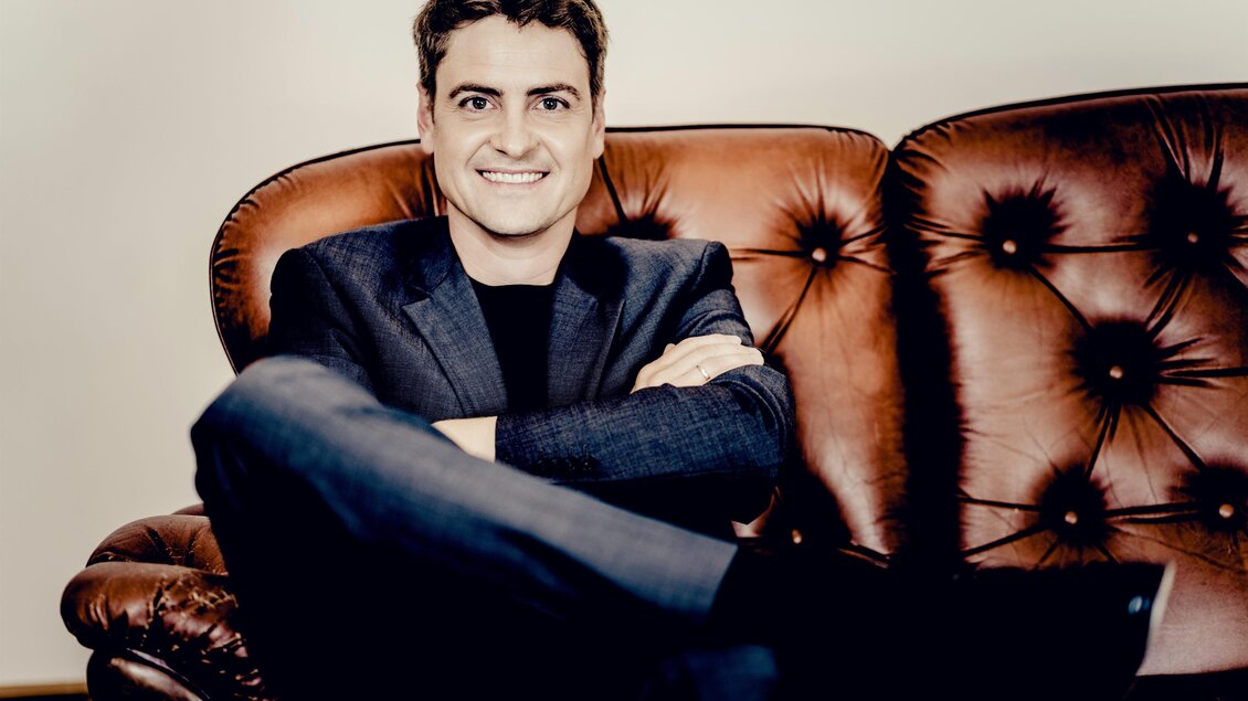 Porträt des Pianisten Christoph Traxler, der auf einem braunen Ledersofa sitzt. | © Andrej Grilc