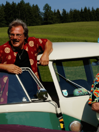 Eine Gruppe von fünf Musikern steht vor einem klassischen VW-Bus. Sie tragen bunte Hemden und lächeln in die Kamera. | © Gemeinde Gamlitz