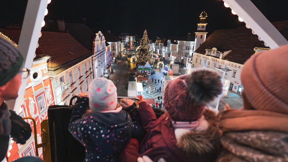 Ein Blick von einem Riesenrad auf einen festlichen Weihnachtsmarkt bei Nacht. Die bunten Lichter und der Weihnachtsbaum schaffen eine fröhliche Atmosphäre. | © TVB Erzberg-Leoben
