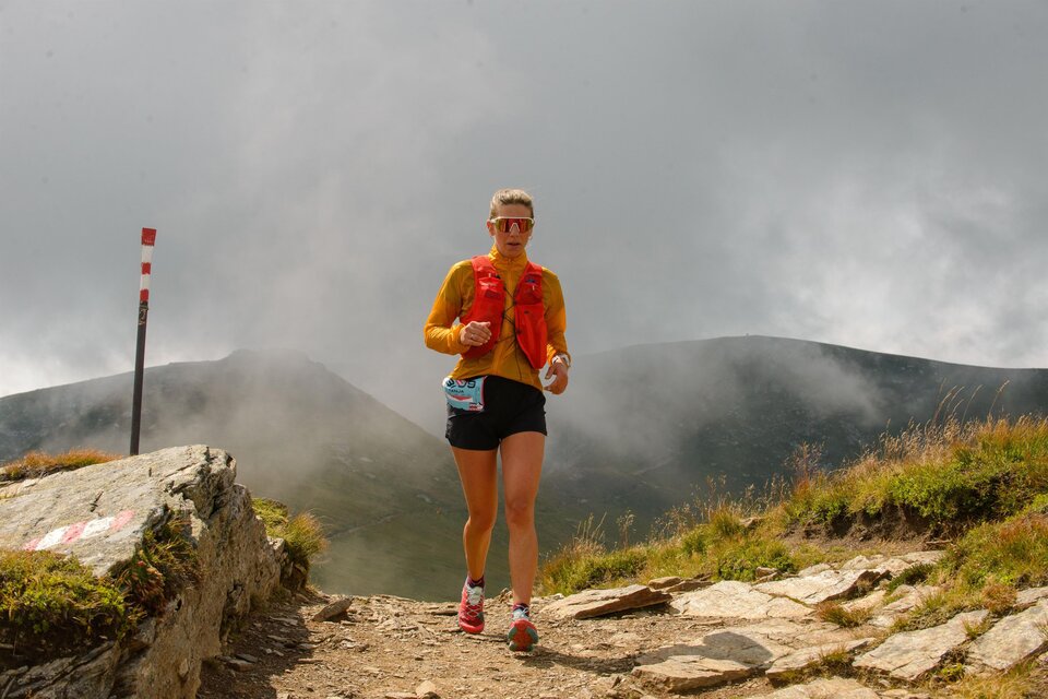 Eine Person joggt auf einem steinigen Pfad in den Bergen. Der Himmel ist bewölkt und die Landschaft ist steinig und grün. | © Christian Prattes
