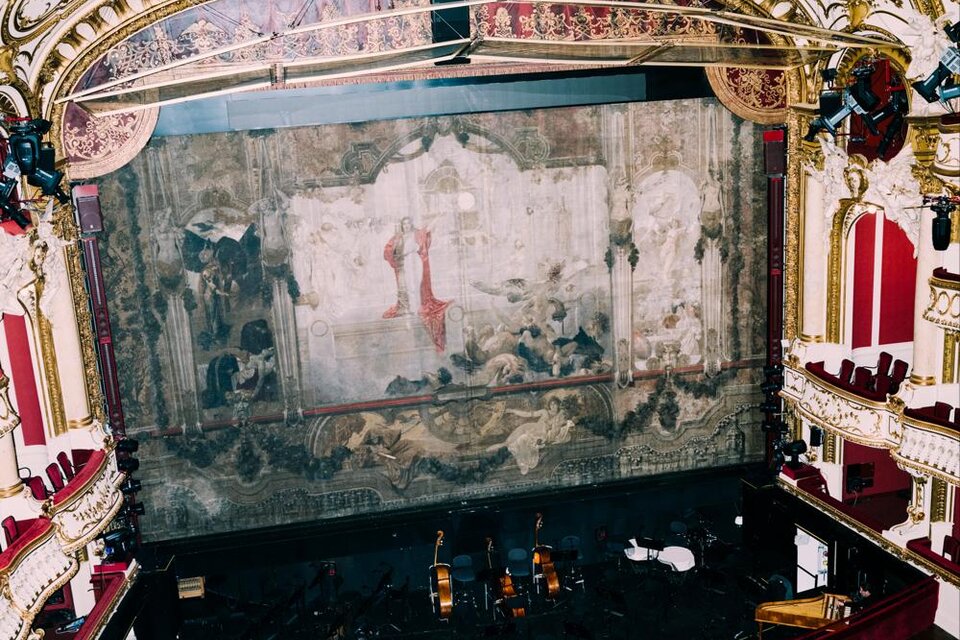 Ein prachtvolles Theater mit einem dekorativen Bühnenvorhang und einem eleganten Zuschauerraum. Die Sitze sind rot und die Wände sind kunstvoll gestaltet. | © Oper Graz