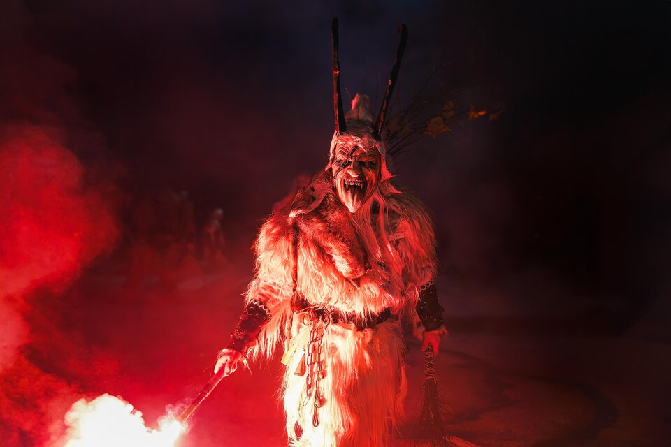 Ein mystischer Charakter in einer Fellkostüm mit einer Maske steht im roten Licht. Der Hintergrund ist dunkel und rauchig, was eine spannende Atmosphäre schafft. | © Stadtgemeinde Bärnbach