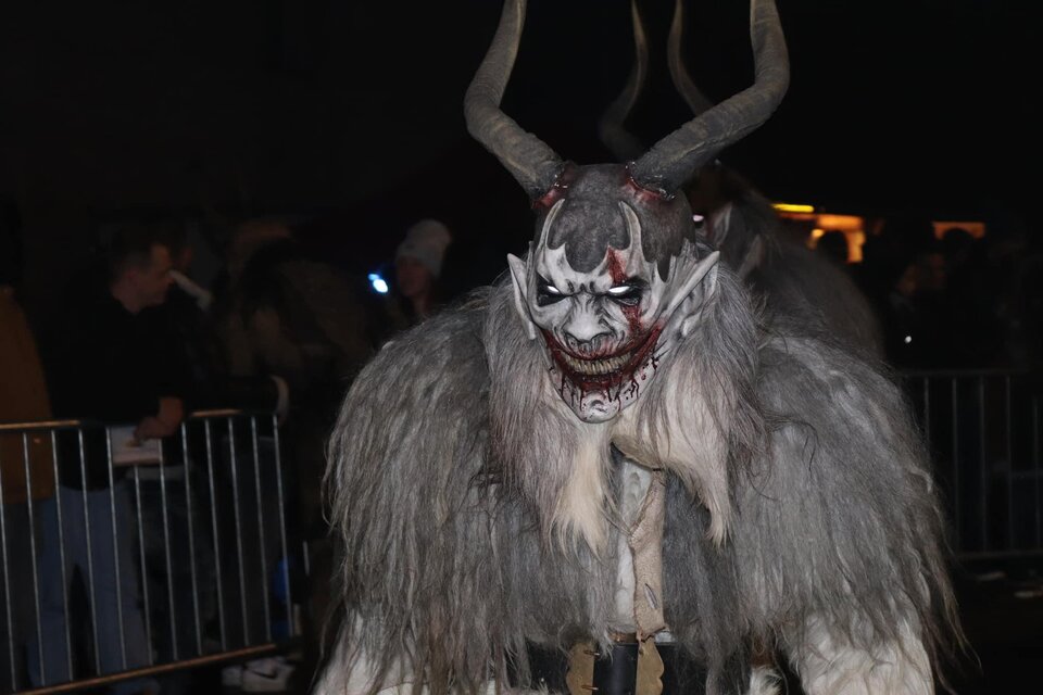 Ein schauriger Charakter mit Hörnern und furchterregendem Gesichtsausdruck. Die Figur trägt einen grauen Pelzmantel und befindet sich in einer Menschenmenge bei Nacht. | © Stoarbruch Teifl| Krampuslauf