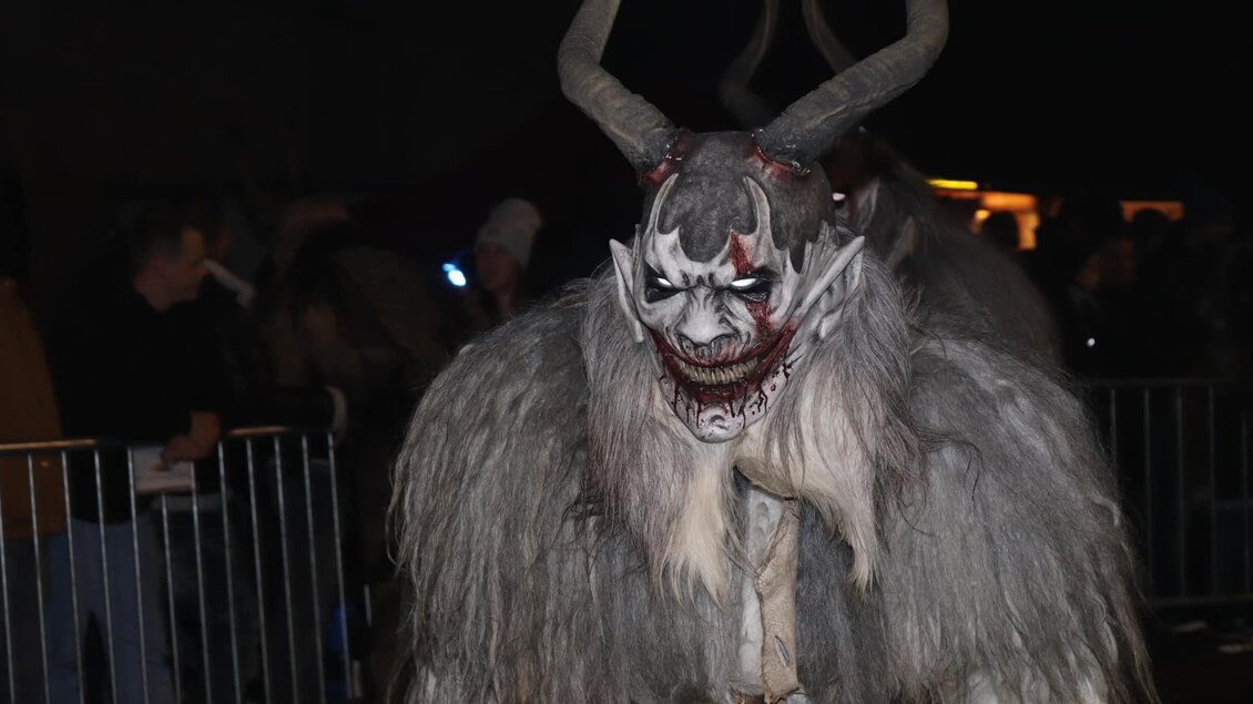 Ein schauriger Charakter mit Hörnern und furchterregendem Gesichtsausdruck. Die Figur trägt einen grauen Pelzmantel und befindet sich in einer Menschenmenge bei Nacht. | © Stoarbruch Teifl| Krampuslauf
